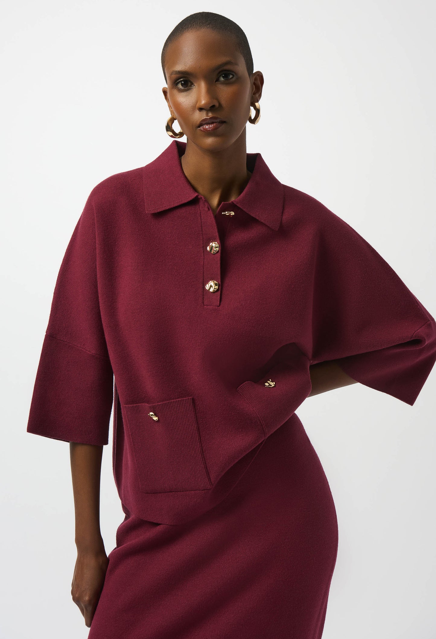 Woman wearing a burgundy dress with gold buttons on a white background