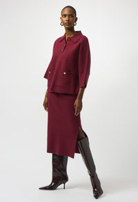 Woman wearing a burgundy outfit with a matching skirt and top on a white background