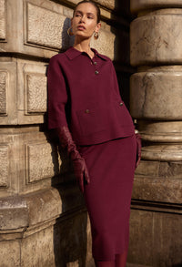 Woman in a burgundy outfit standing against stone columns