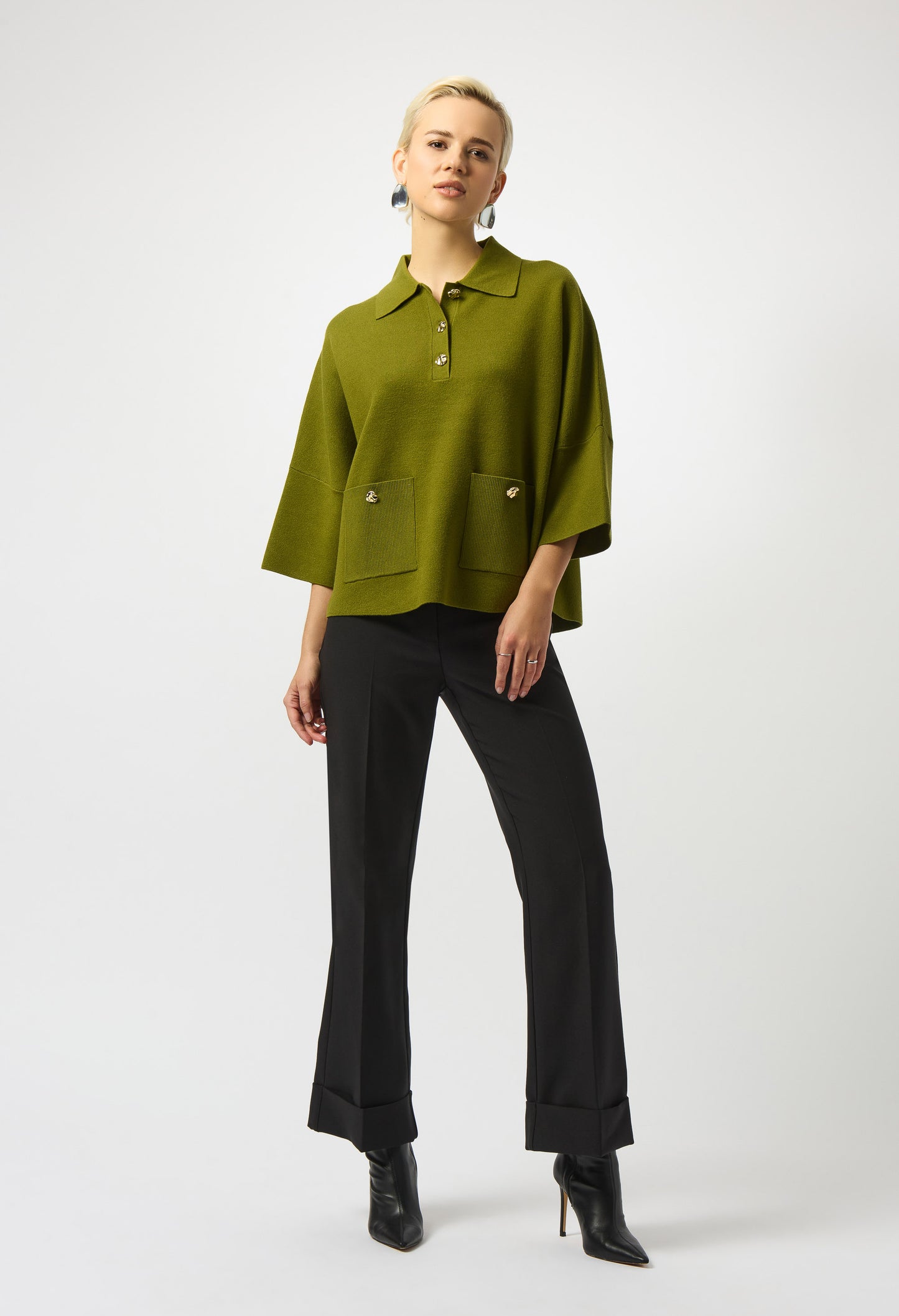 Woman wearing a green blouse and black pants on a white background