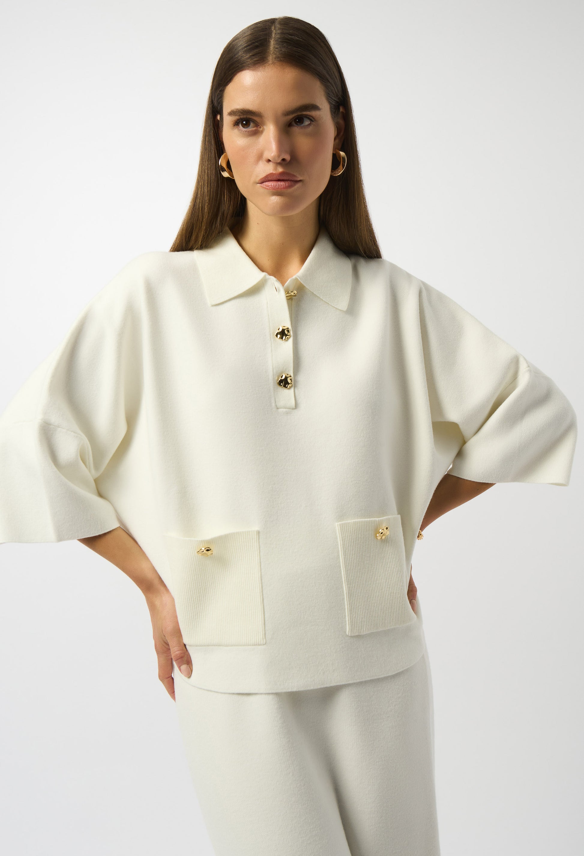Woman wearing a white outfit with a jacket and pants on a plain background