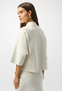 Woman wearing a white cape over a plain background