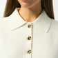 Close-up of a white blouse with gold buttons on a plain background