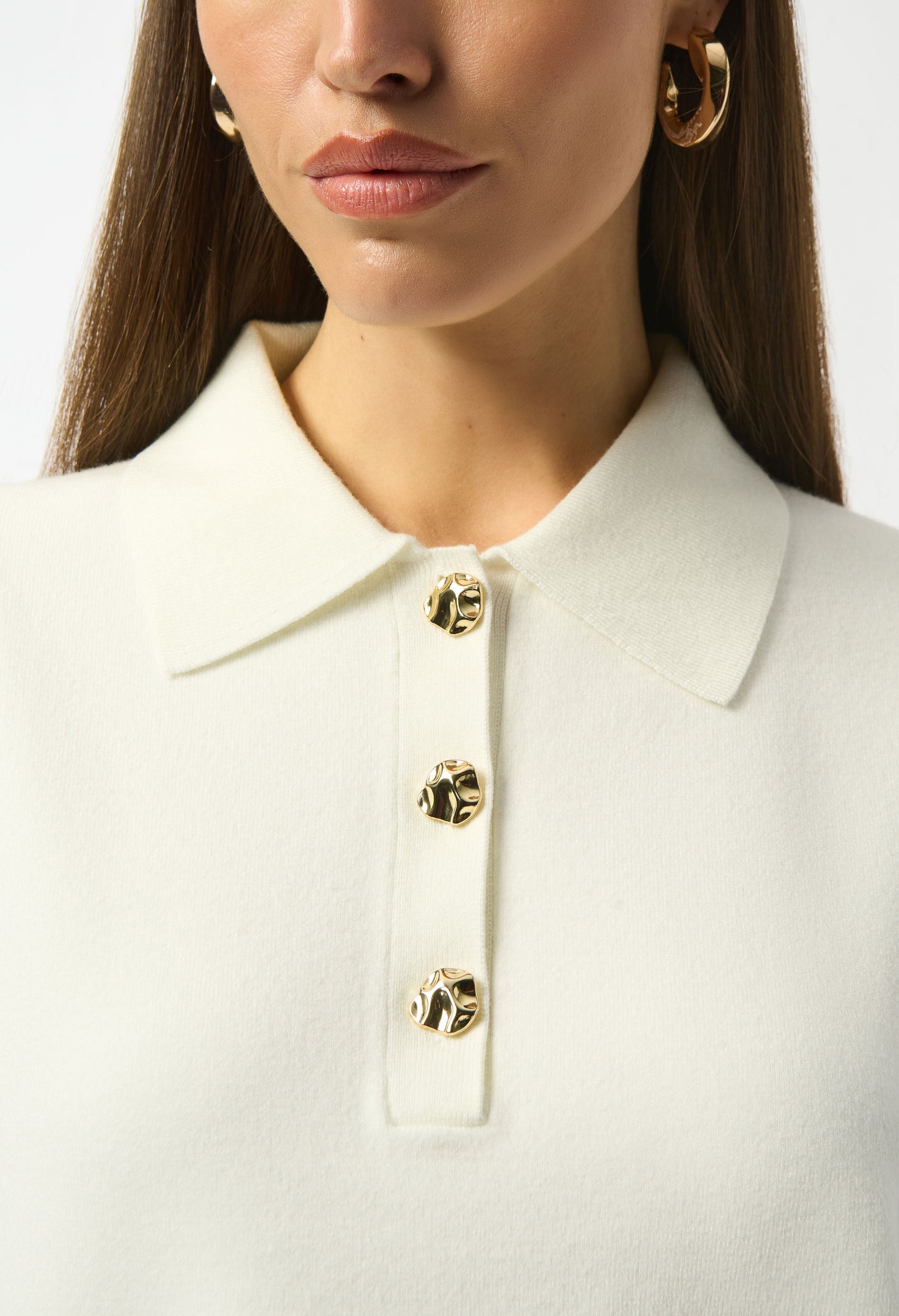 Close-up of a white blouse with gold buttons on a plain background