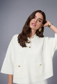 Woman wearing a white outfit with gold buttons against a gray background