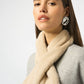 Woman wearing a beige scarf and earrings on a white background