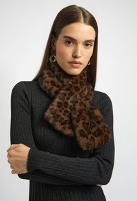 Woman wearing a dark gray sweater and leopard print scarf against a white background