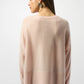 Woman wearing a light pink sweater on a white background