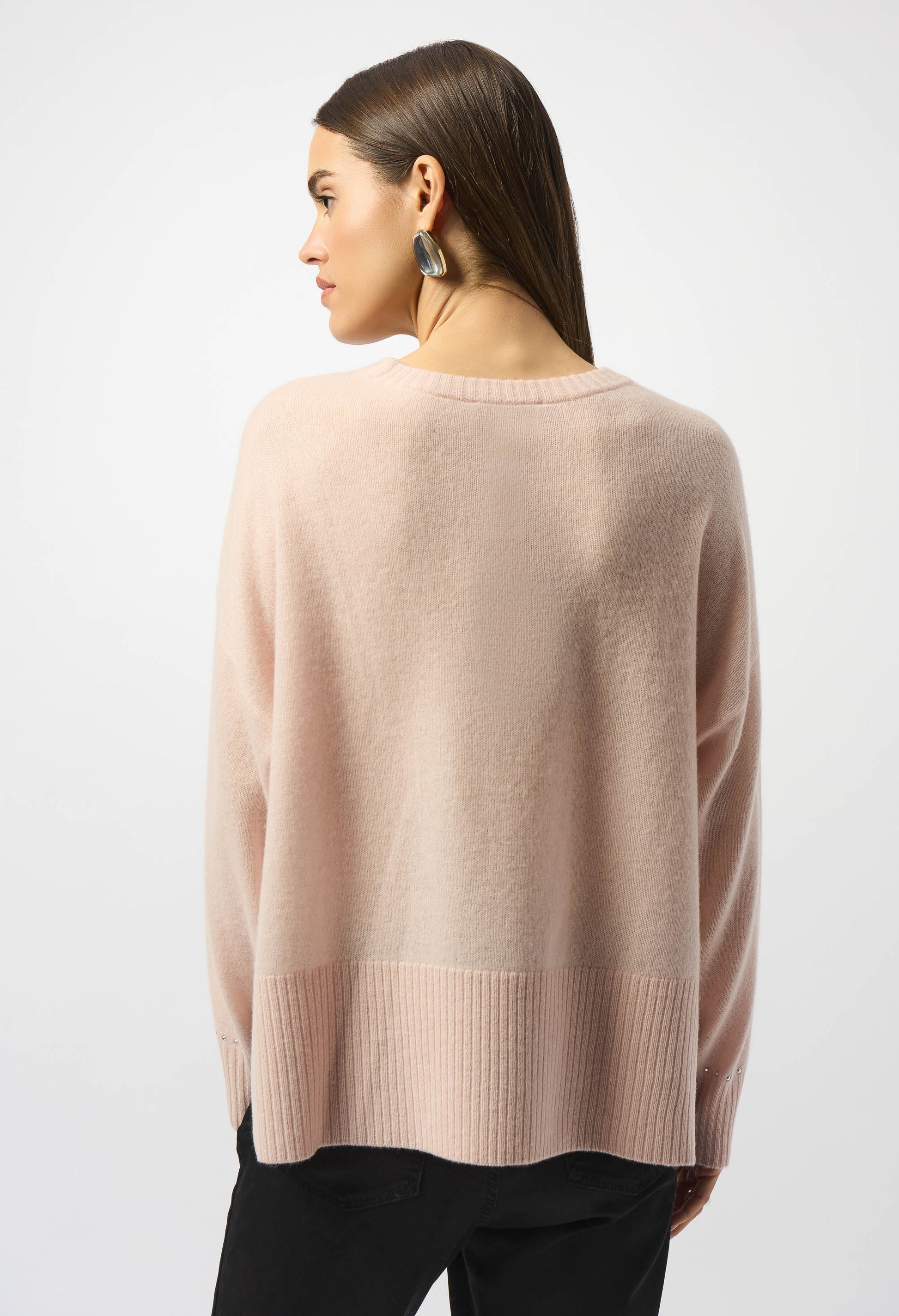 Woman wearing a light pink sweater on a white background