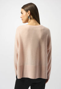Woman wearing a light pink sweater on a white background