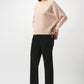 Woman wearing a light pink sweater and black pants on a white background