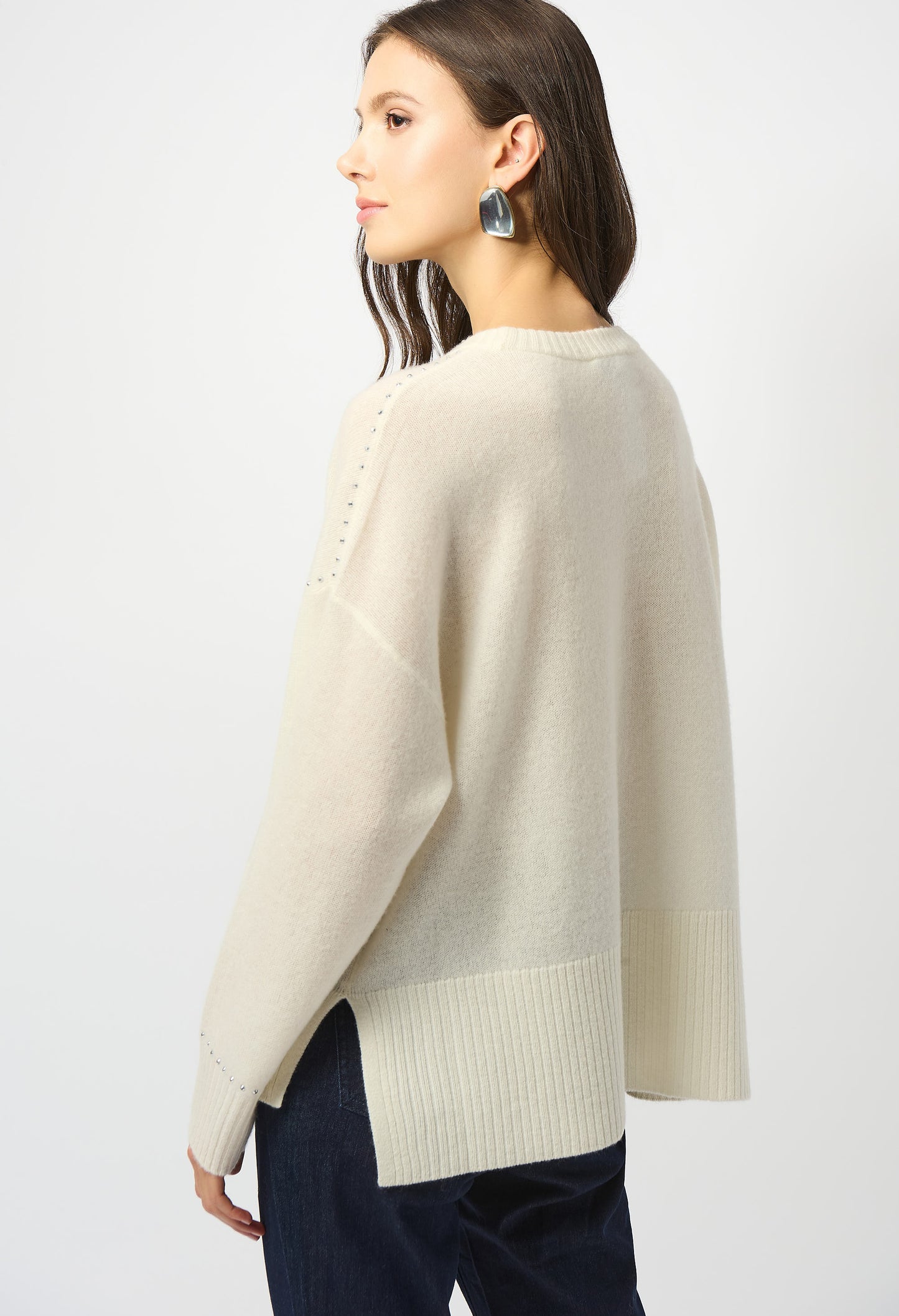 Woman wearing a beige poncho over a dark outfit on a white background