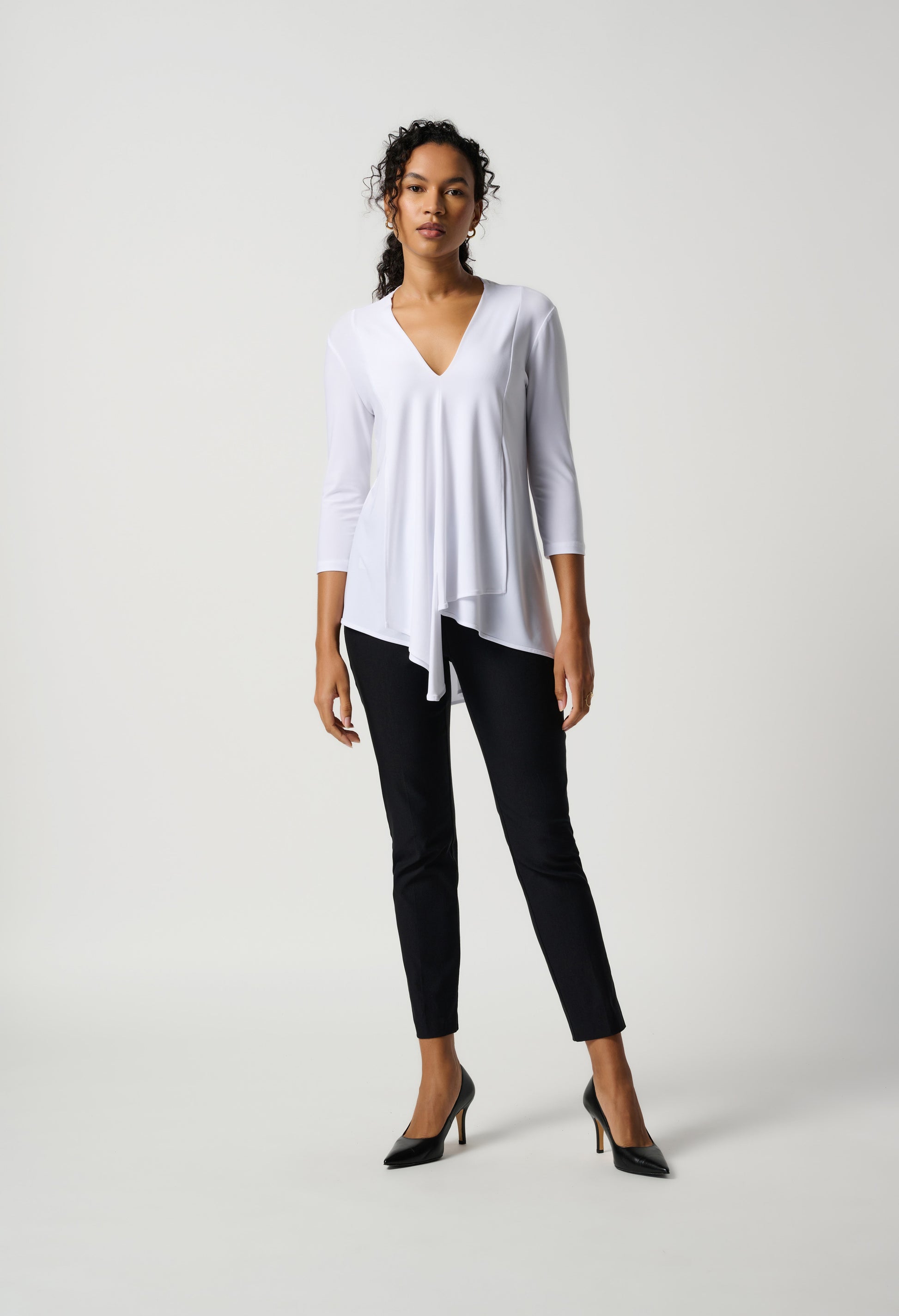 Woman wearing a white top and black pants on a white background
