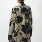 Person wearing a long, patterned coat with black floral designs on a white background
