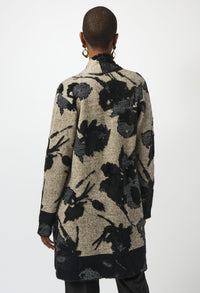 Person wearing a long, patterned coat with black floral designs on a white background