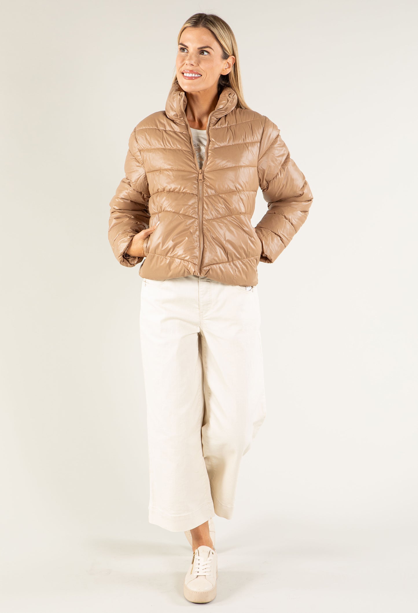 Woman wearing a beige puffer jacket on a white background