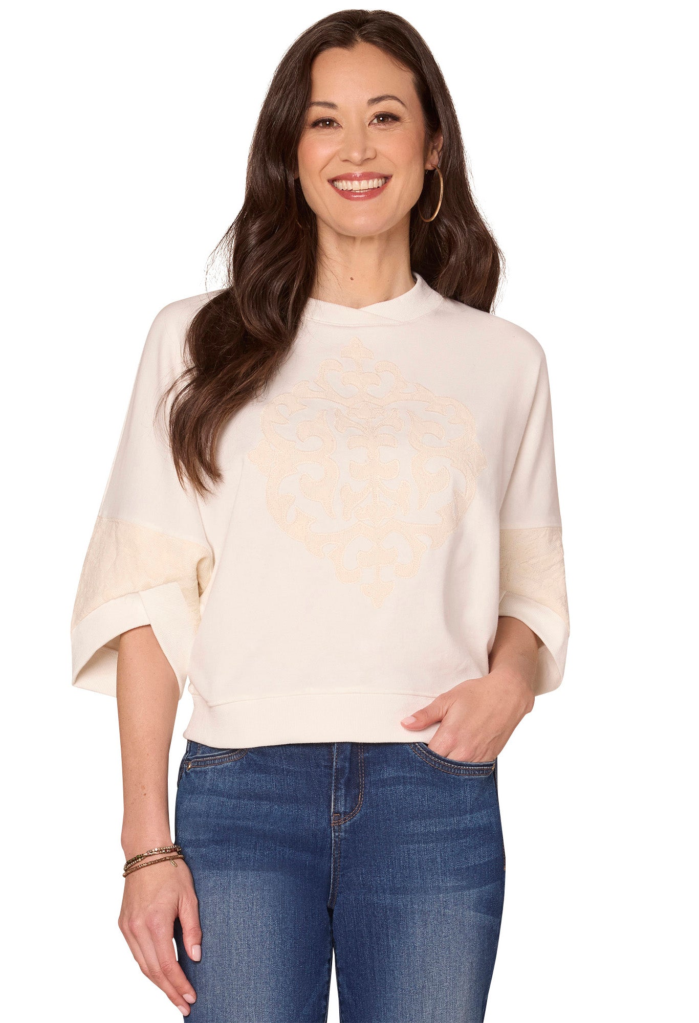 Woman wearing a cream sweater and blue jeans on a white background