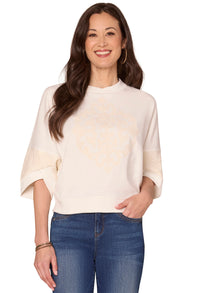 Woman wearing a cream sweater and blue jeans on a white background
