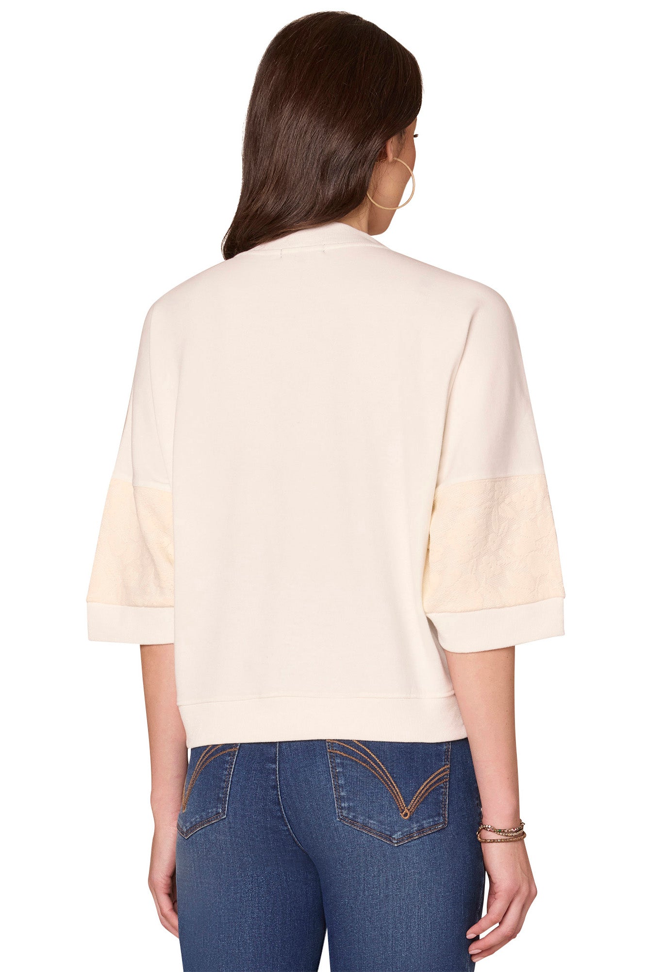 Woman wearing a beige top and blue jeans on a white background