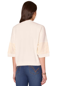 Woman wearing a beige top and blue jeans on a white background