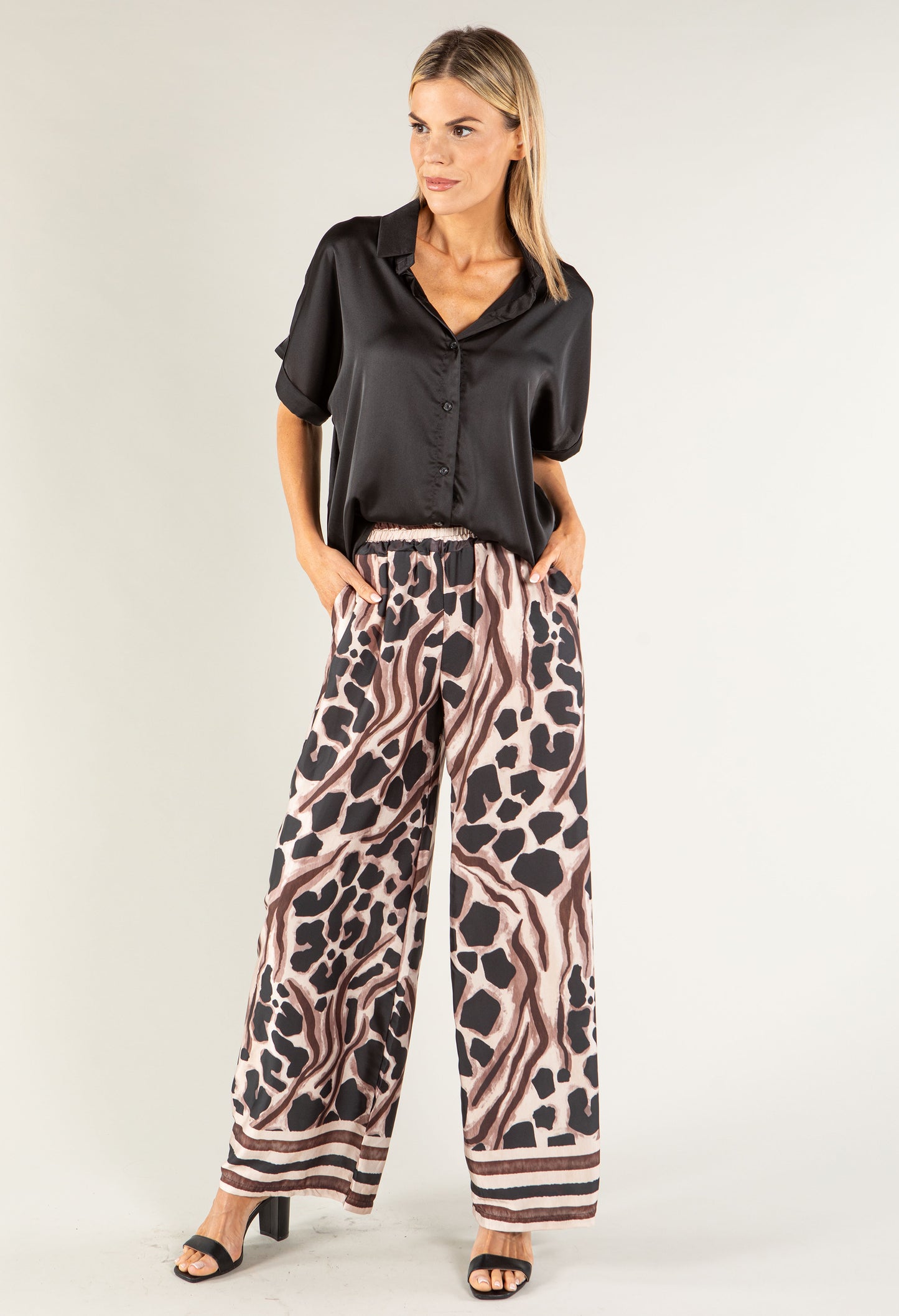 Woman wearing a black top and leopard print pants on a white background