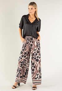 Woman wearing a black top and leopard print pants on a white background
