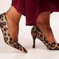Leopard print high-heeled shoes worn with a red skirt on a white background