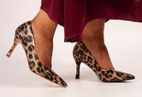 Leopard print high-heeled shoes worn with a red skirt on a white background
