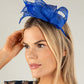 Woman wearing a blue fascinator on a plain background