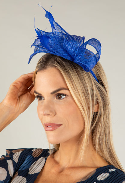 Woman wearing a blue fascinator on a plain background