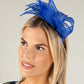 Woman wearing a blue fascinator on a plain background