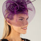 Woman wearing a decorative fascinator with a plain background