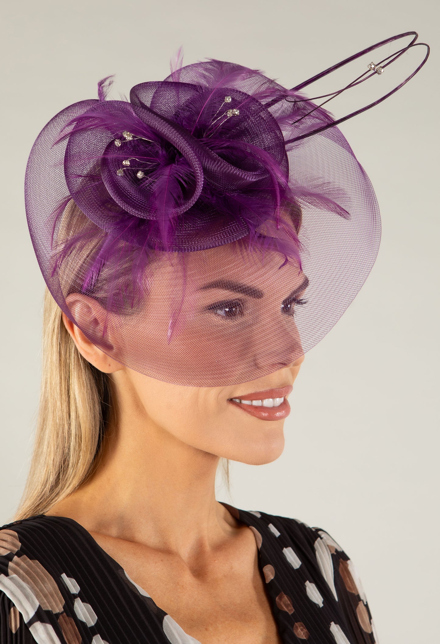 Woman wearing a decorative fascinator with a plain background