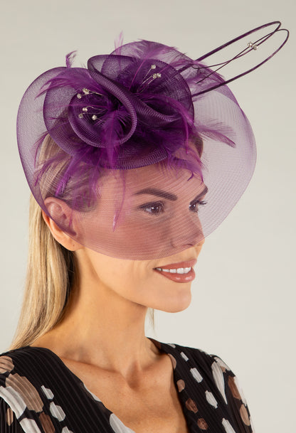 Woman wearing a decorative fascinator with a plain background