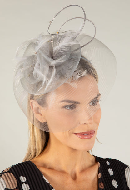 Woman wearing a decorative headpiece with a veil against a neutral background