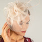 Woman wearing a decorative fascinator with a plain background