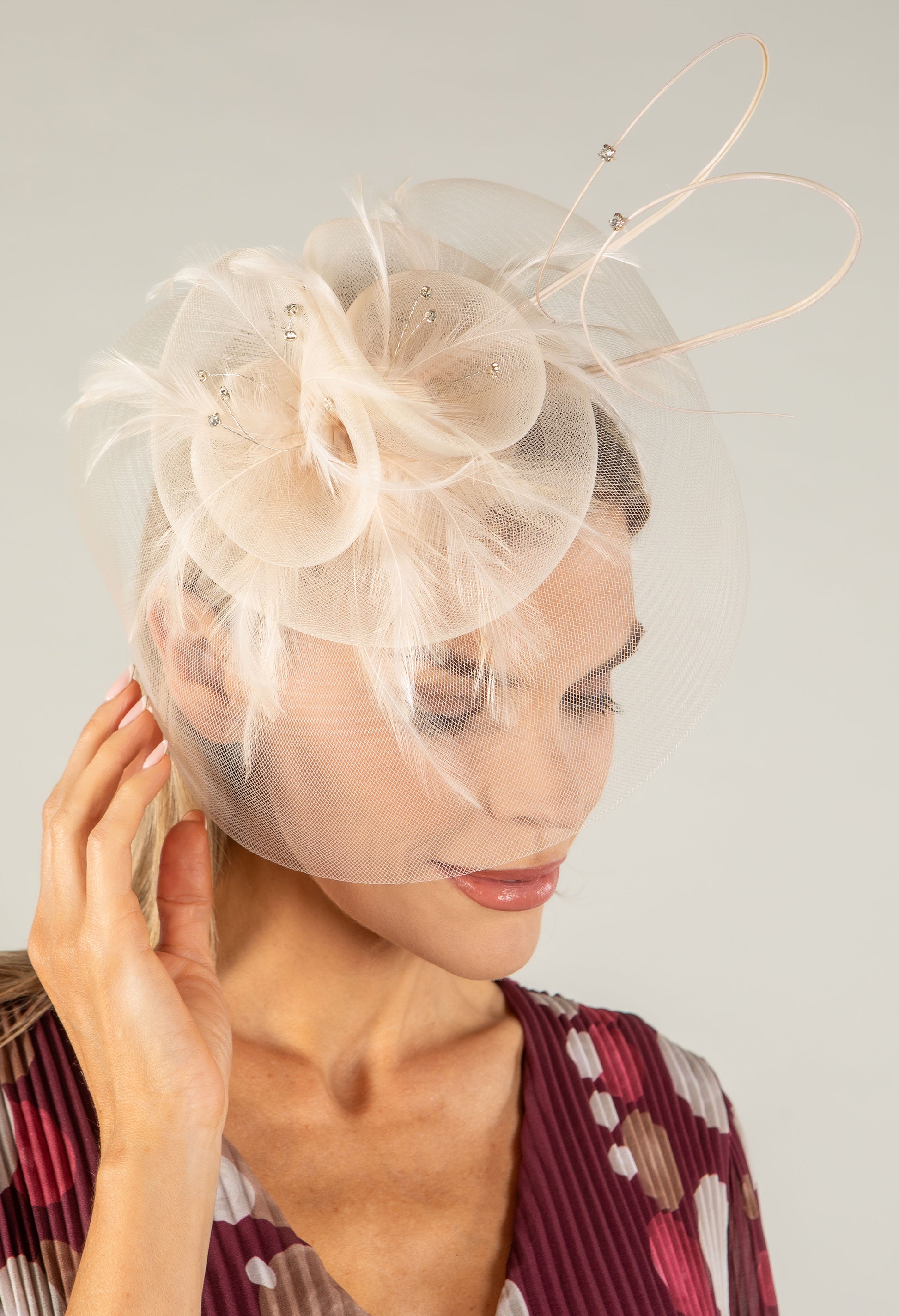 Woman wearing a decorative fascinator with a plain background