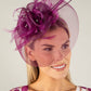 Woman wearing a decorative fascinator with a plain background