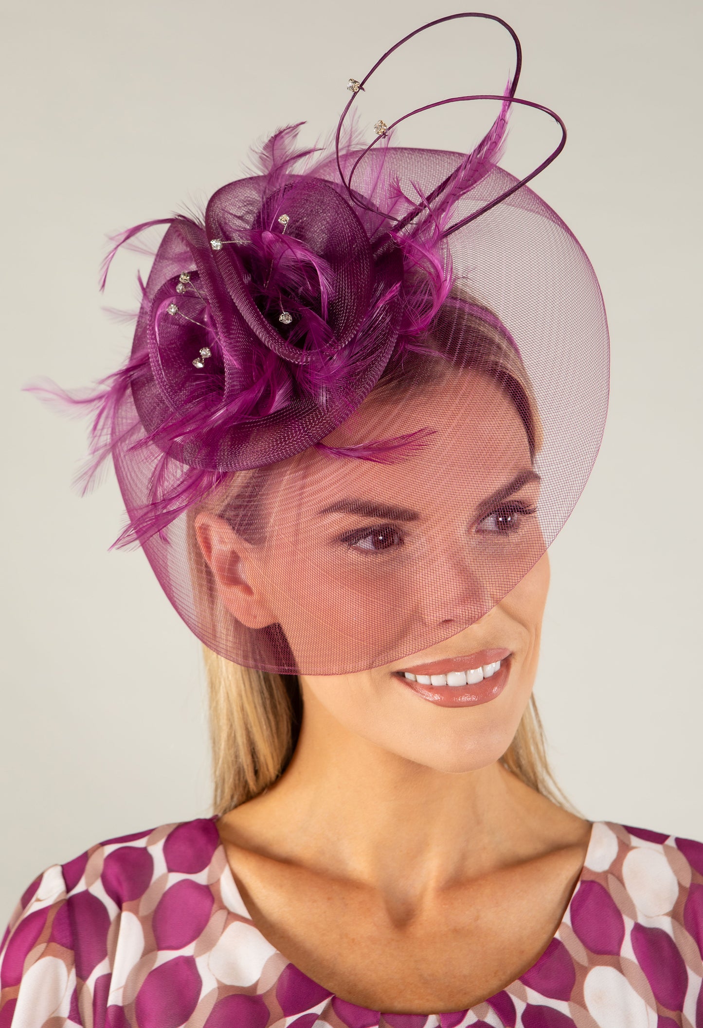Woman wearing a decorative fascinator with a plain background