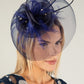 Woman wearing a decorative fascinator with a plain background