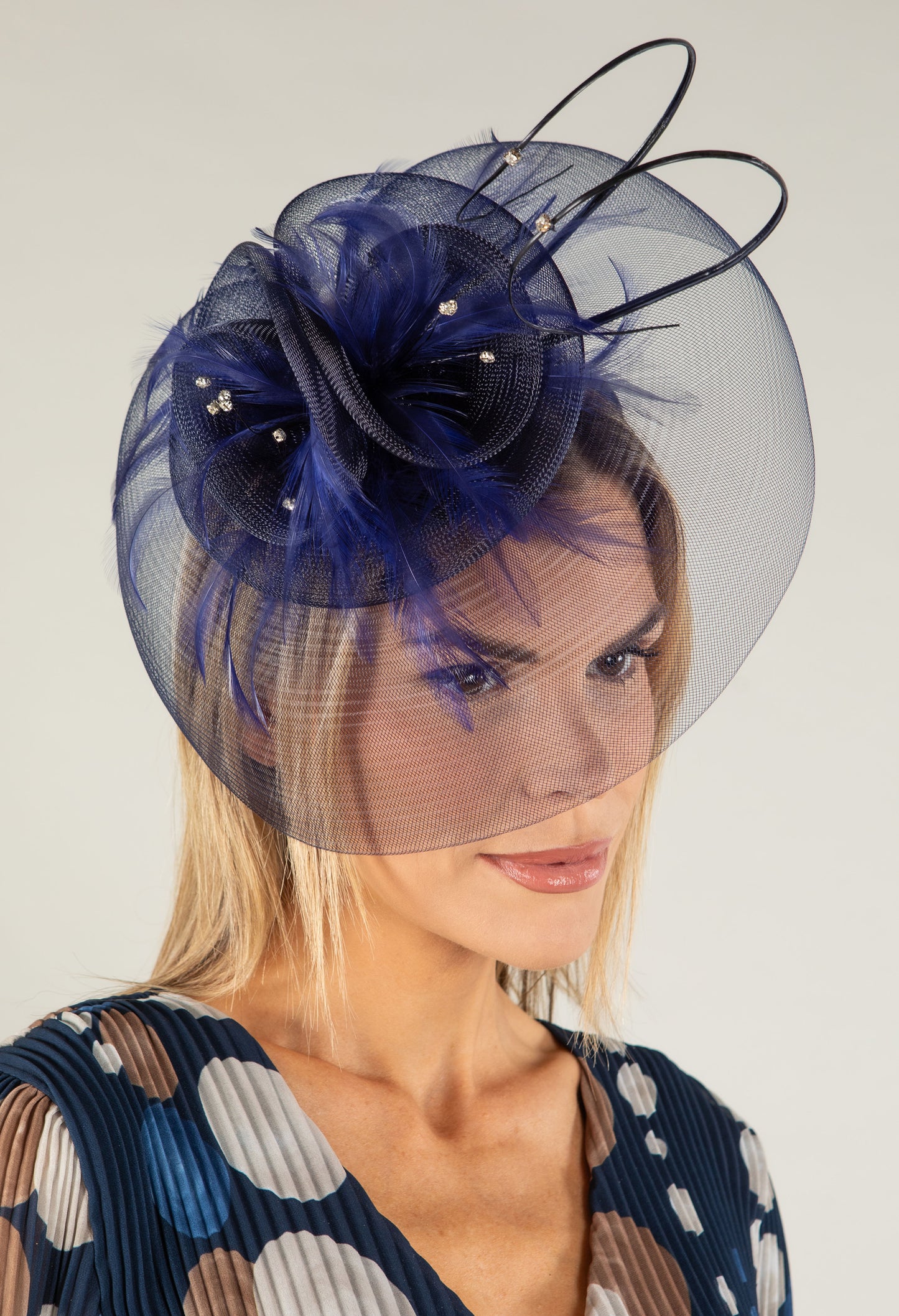 Woman wearing a decorative fascinator with a plain background