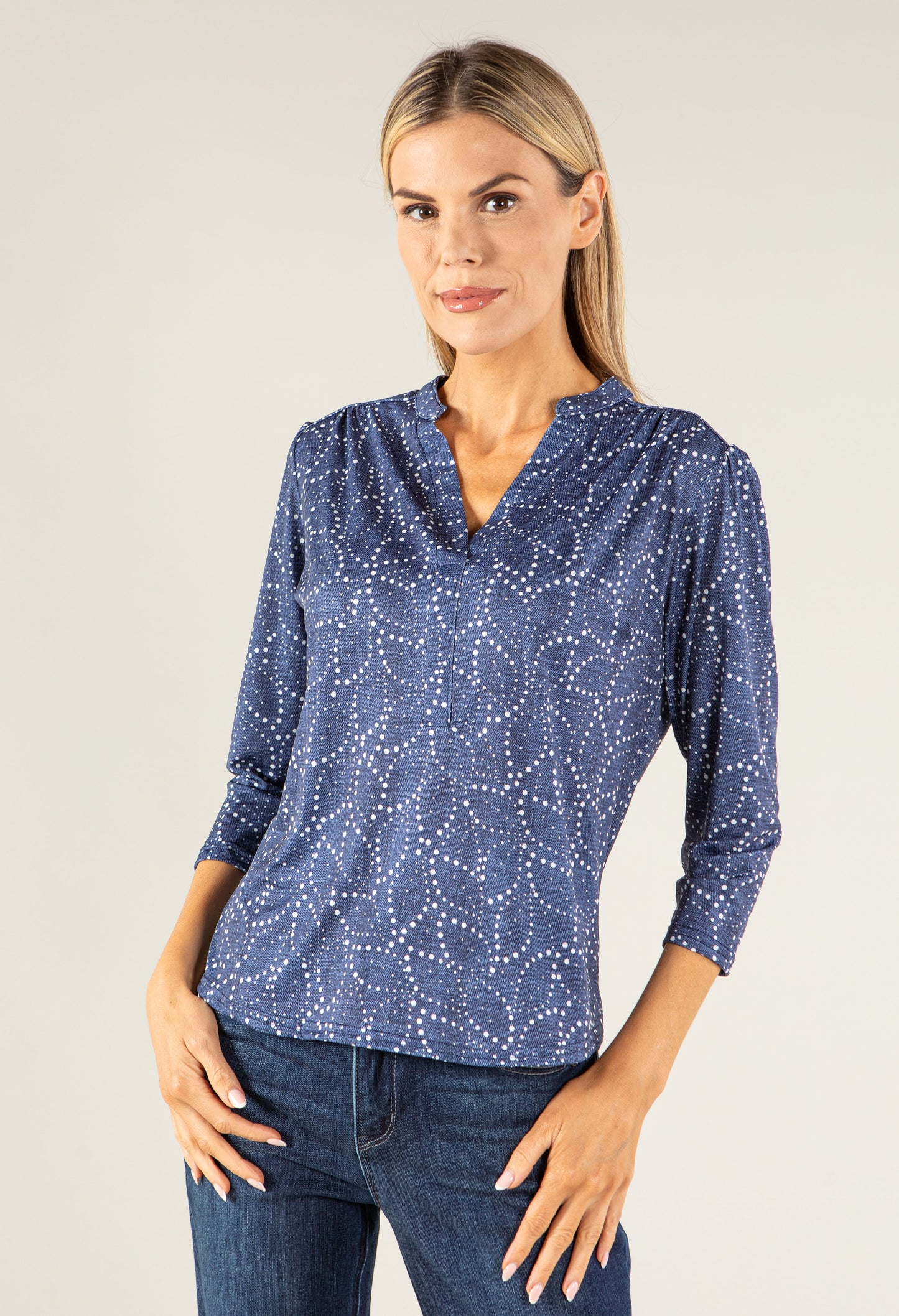 Woman wearing a blue patterned blouse and jeans against a plain background