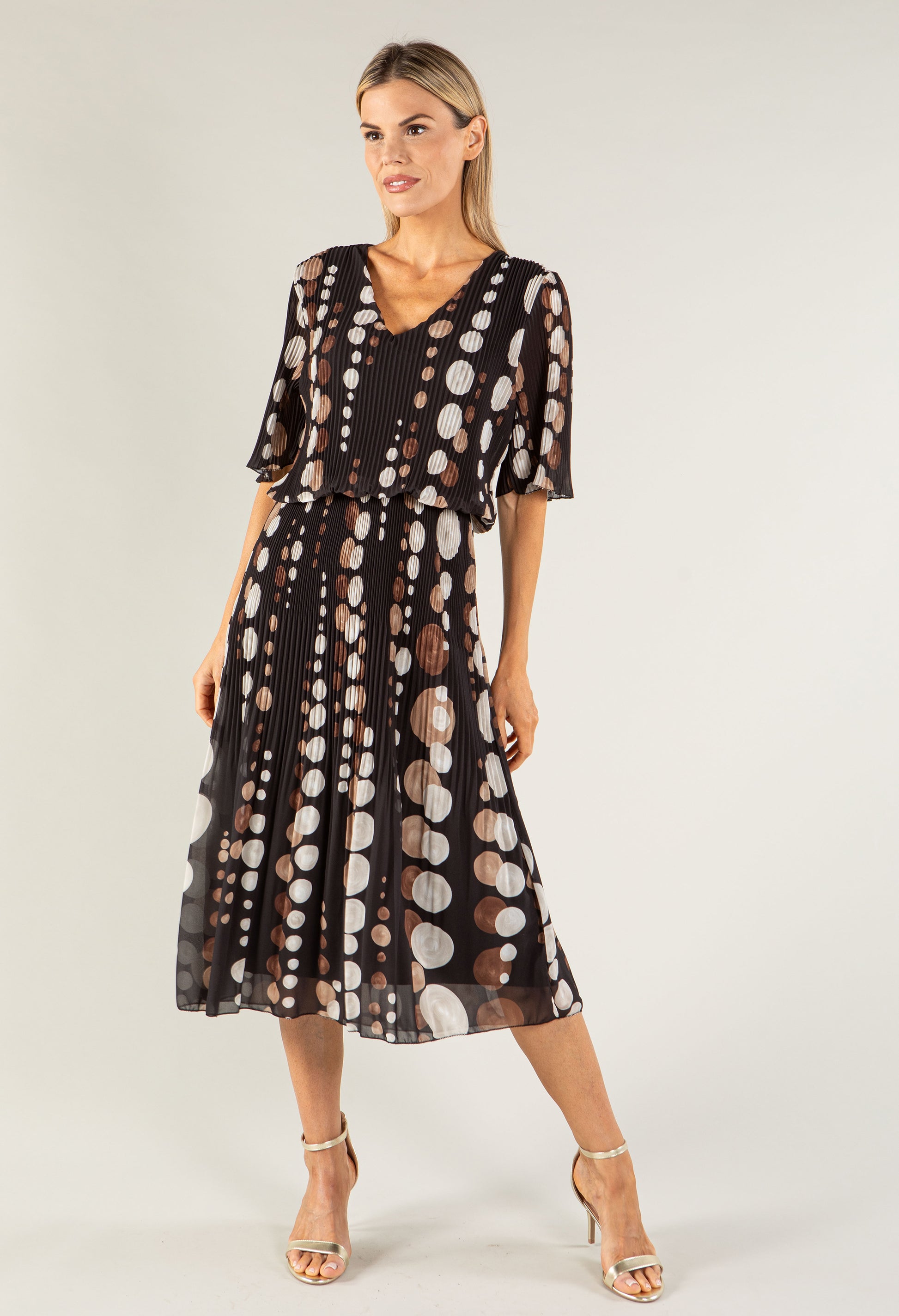 Woman wearing a black dress with white polka dots on a white background