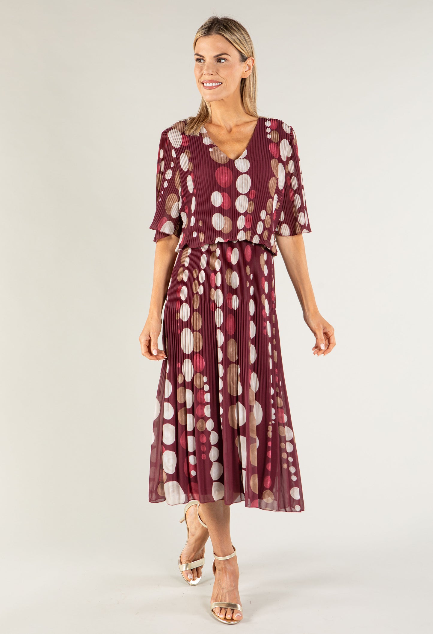 Woman wearing a burgundy dress with a polka dot pattern on a white background