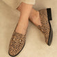 Leopard print loafers worn by a person on a neutral background