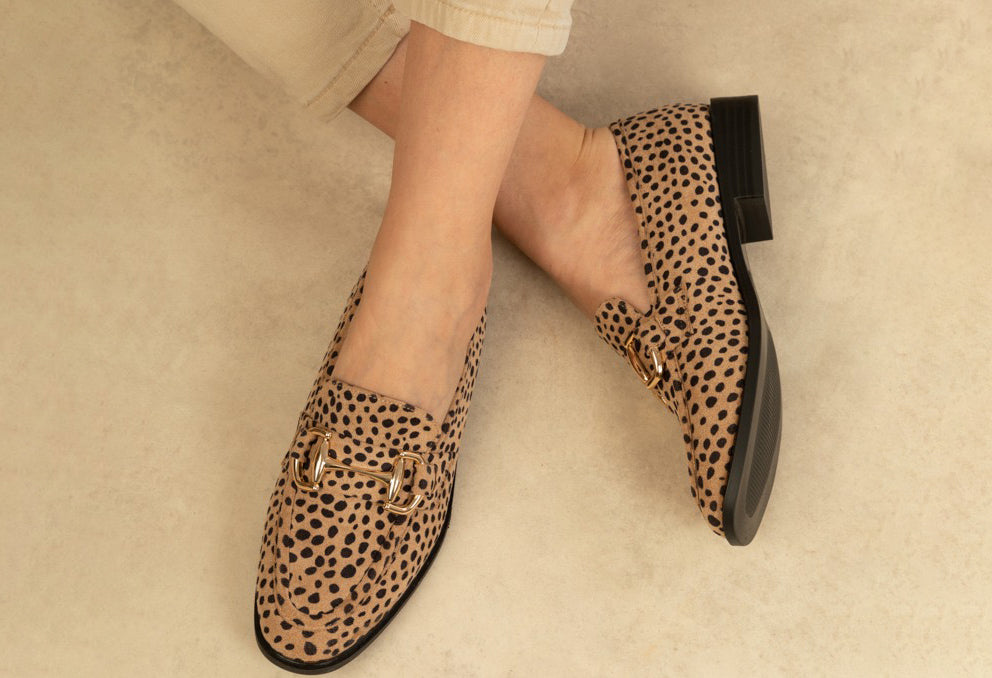 Leopard print loafers worn by a person on a neutral background