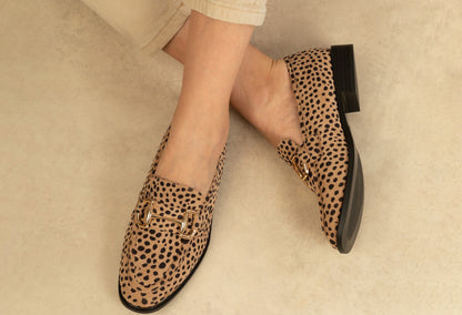 Leopard print loafers worn by a person on a neutral background