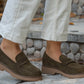 Brown loafers worn with light-colored pants on a stone step.
