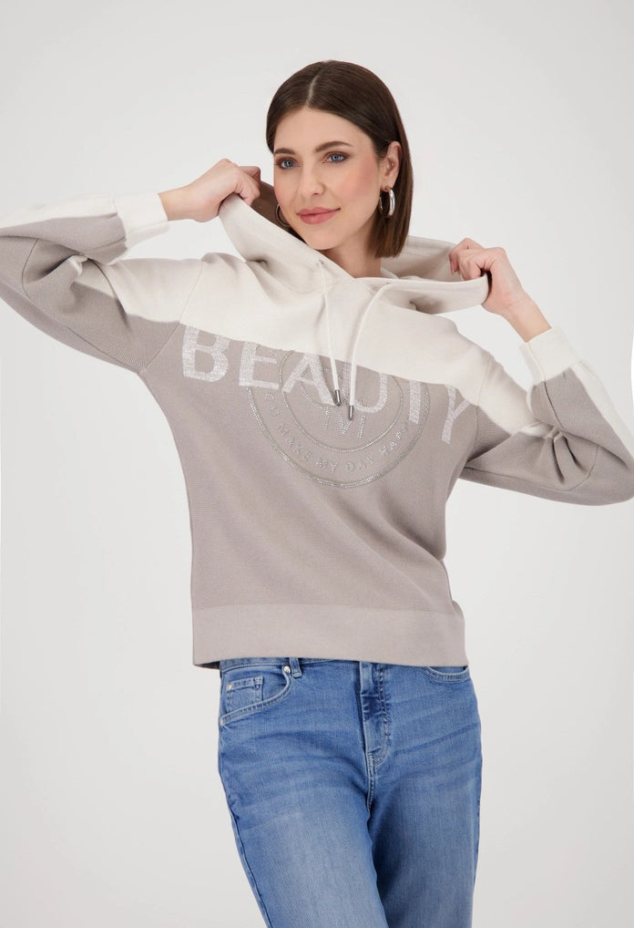 Woman wearing a gray hoodie with 'BEAUTY' text and blue jeans on a white background