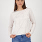 Woman wearing a white sweater with lace details and blue jeans on a white background